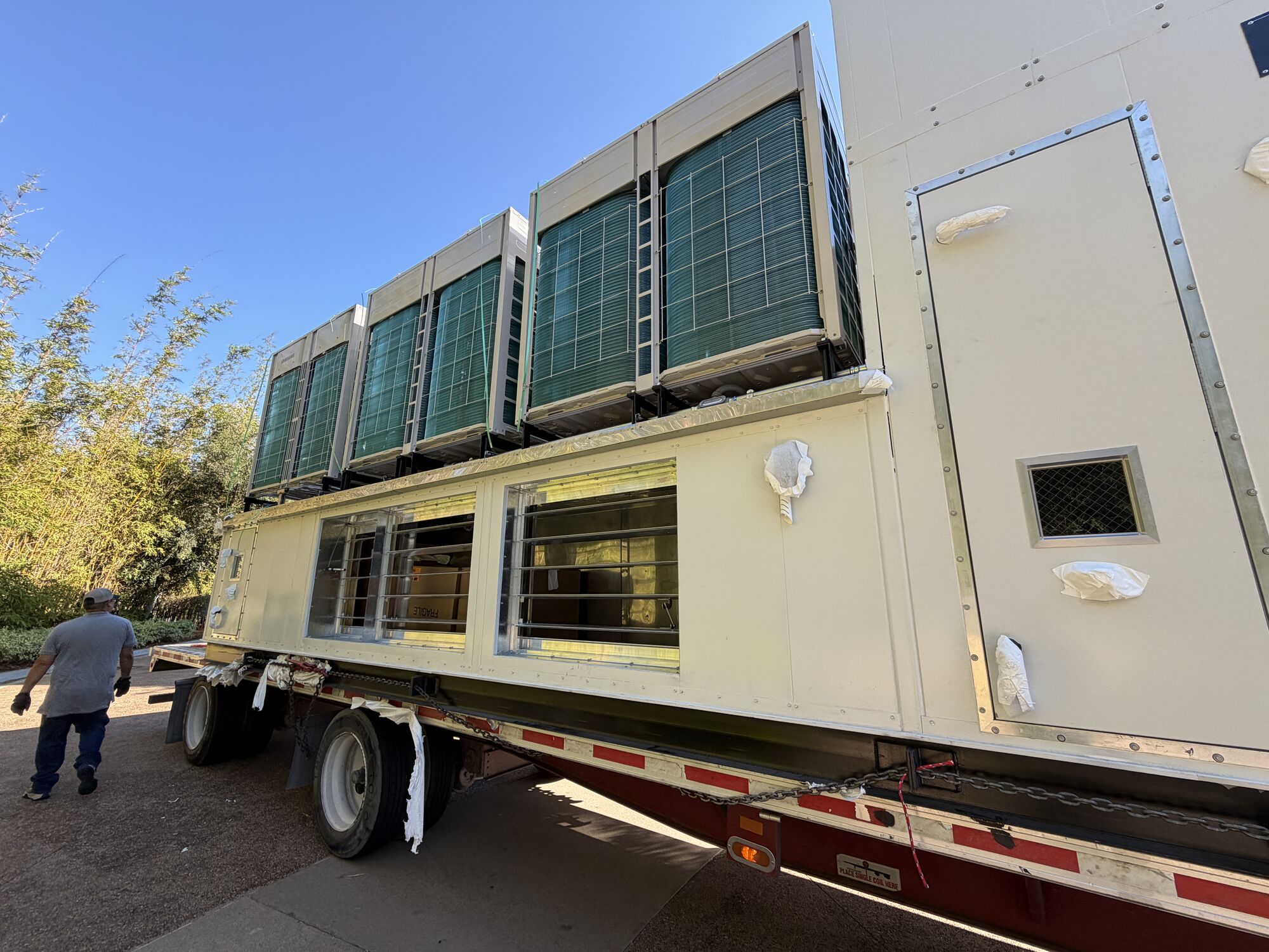 Replacement rooftop unit arriving by flatbed at an occupied office building