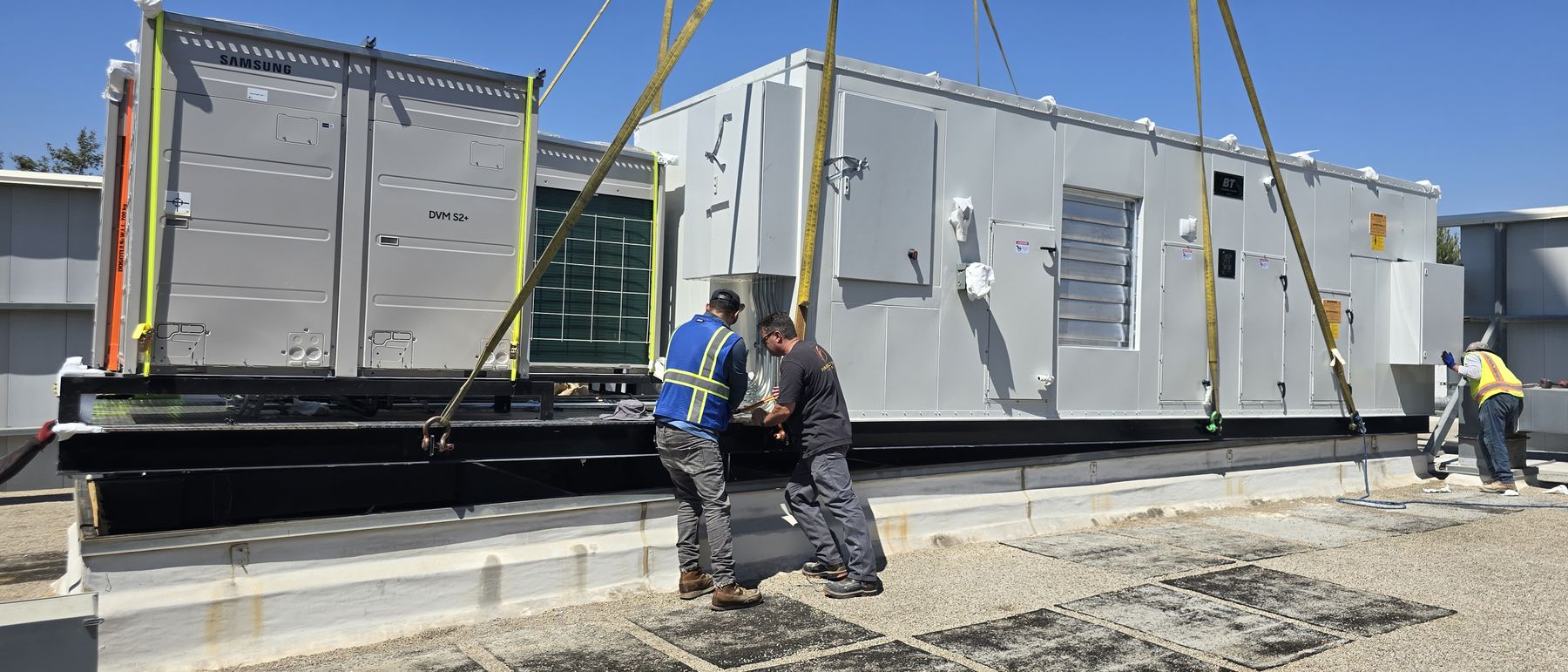 Crew setting an all-electric replacement rooftop unit onto the existing curb
