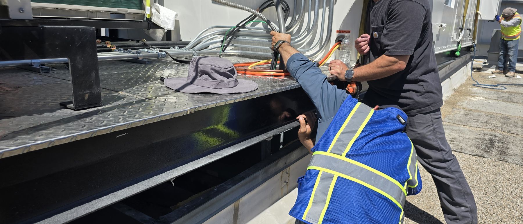 Technicians making connections at the existing roof curb during a changeout