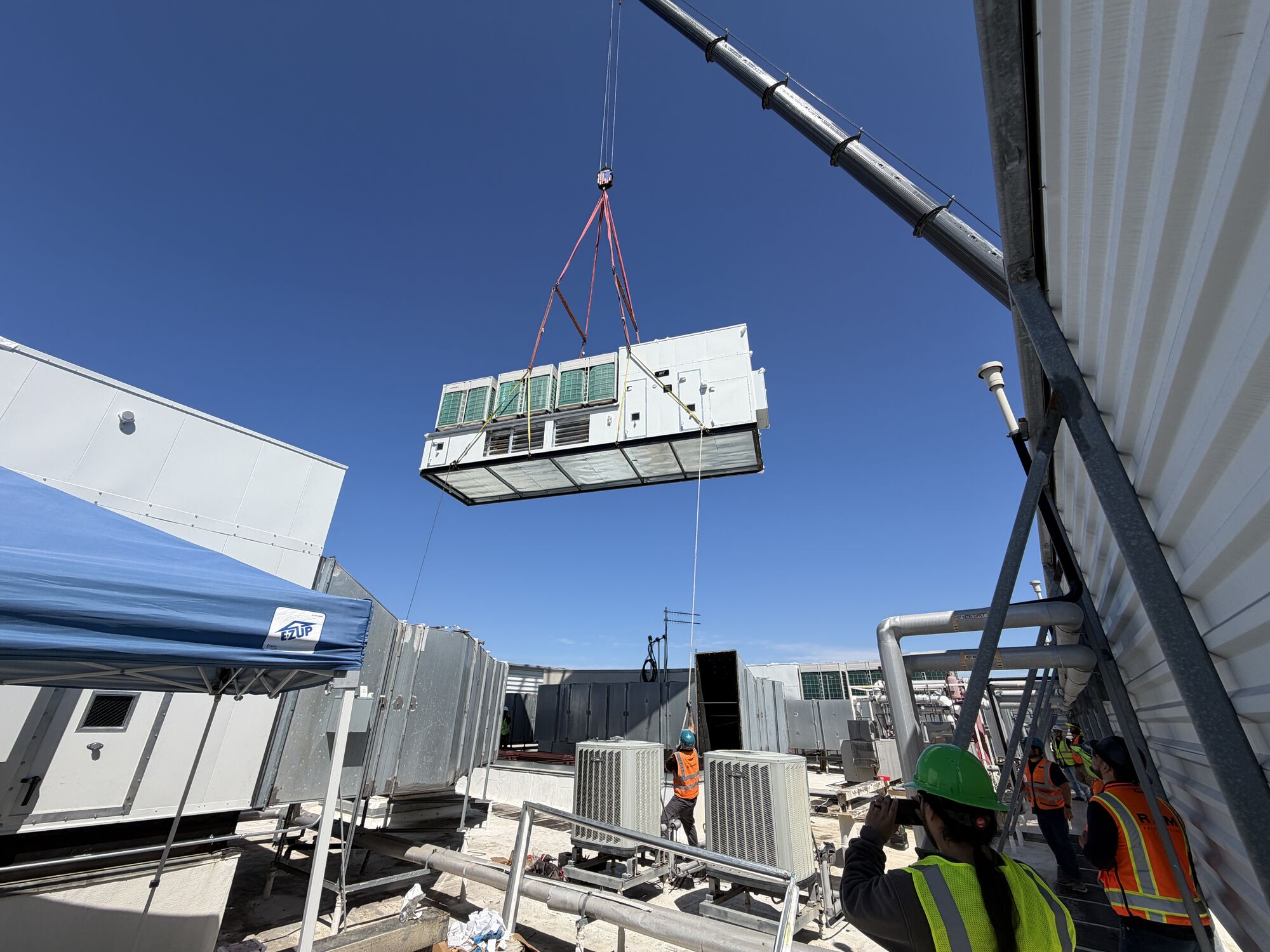 Packaged rooftop unit rigged from a flatbed trailer for a rooftop changeout on an occupied building