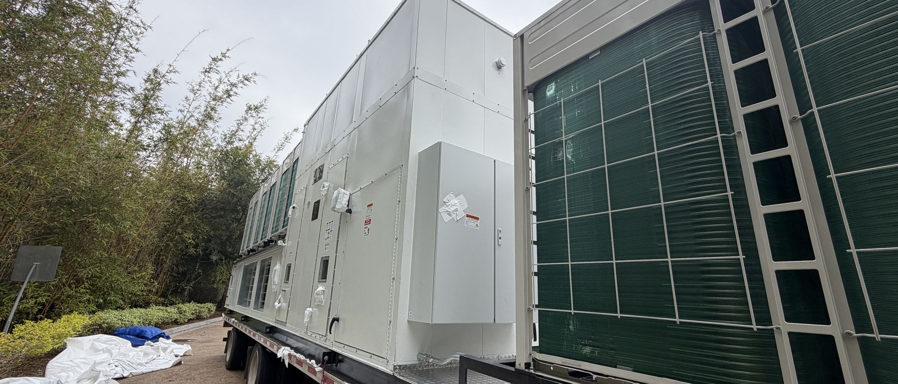 Full-length replacement rooftop unit on a flatbed, condenser coils and integrated sections visible end to end