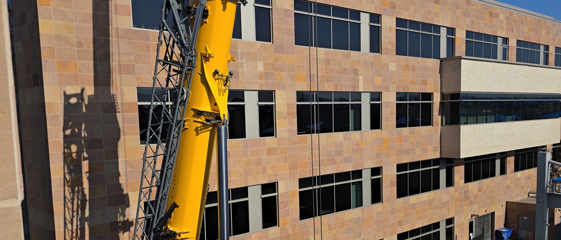 Mobile crane rigged alongside an occupied mid-rise office building for a single rooftop mobilization