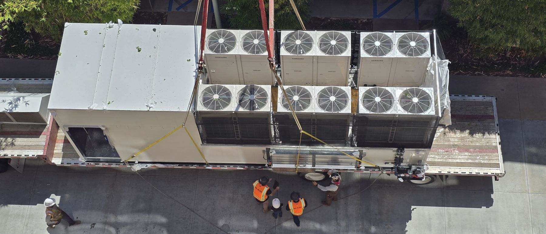 Replacement rooftop unit flying over an occupied building while crew stand clear below