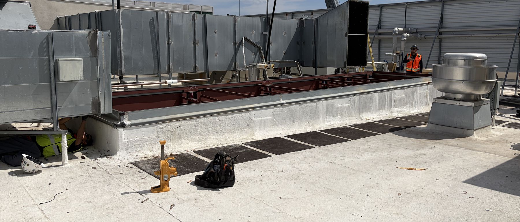 Rooftop opened for a unit changeout, existing structural steel and ductwork exposed with the crane rigged overhead