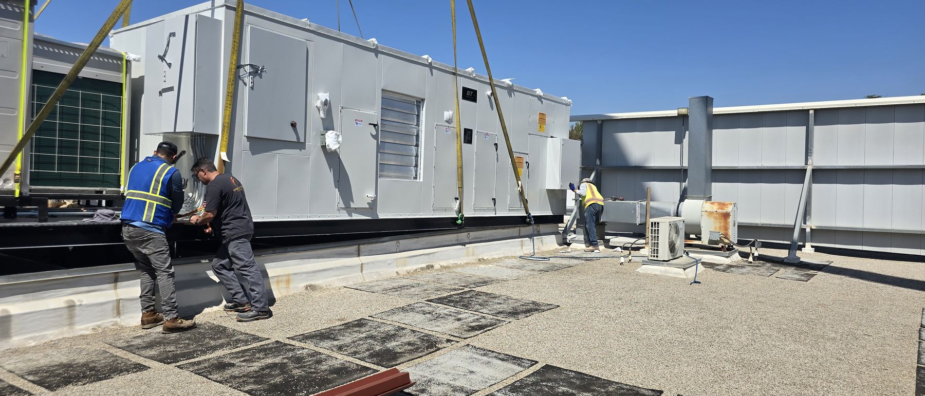 Crew guiding a replacement rooftop unit down onto the existing curb
